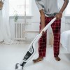 Barefoot man using vacuum cleaner