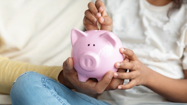 Girl and father putting a coin into piggy bank