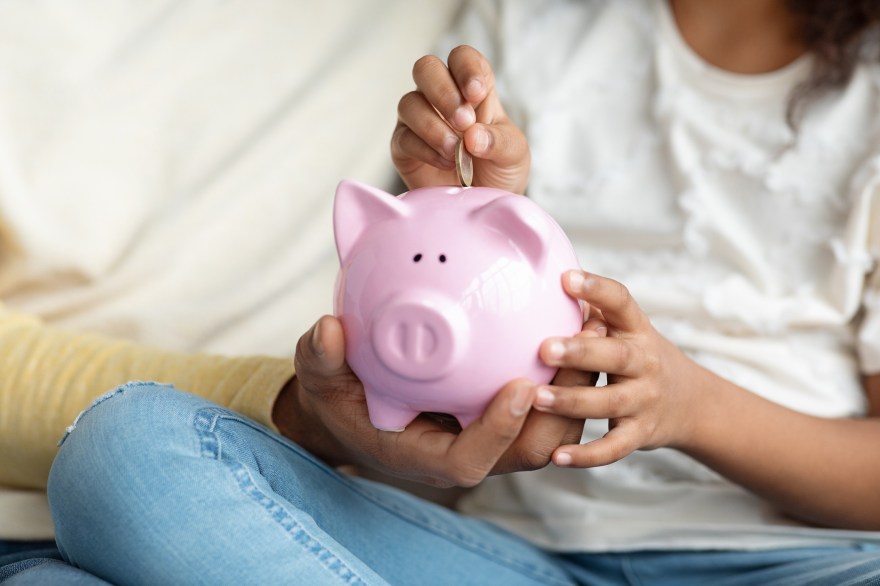 Girl and father putting a coin into piggy bank