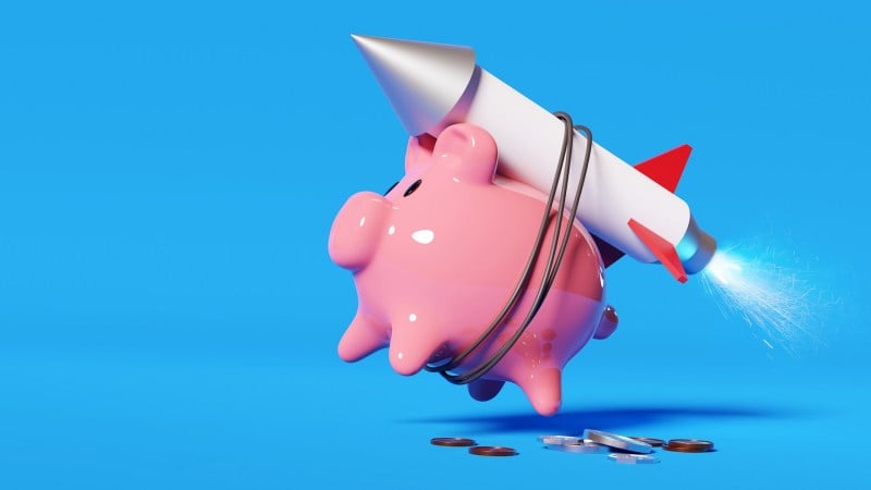 A piggy bank attached to a rocket, representing a rising credit score.