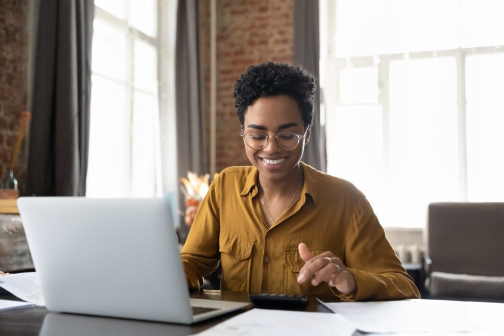 A young woman looking at her finances while sitting at a dining table