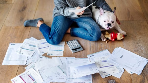 Woman managing the debt while sitting on the floor with her dog and a pile of bills