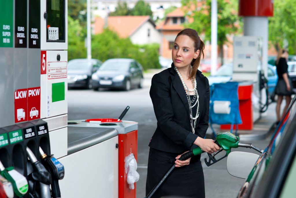 woman pumping gas with expensive prices, prompting discussion on how to manage money