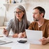 Married couple managing bills in their dinning room table