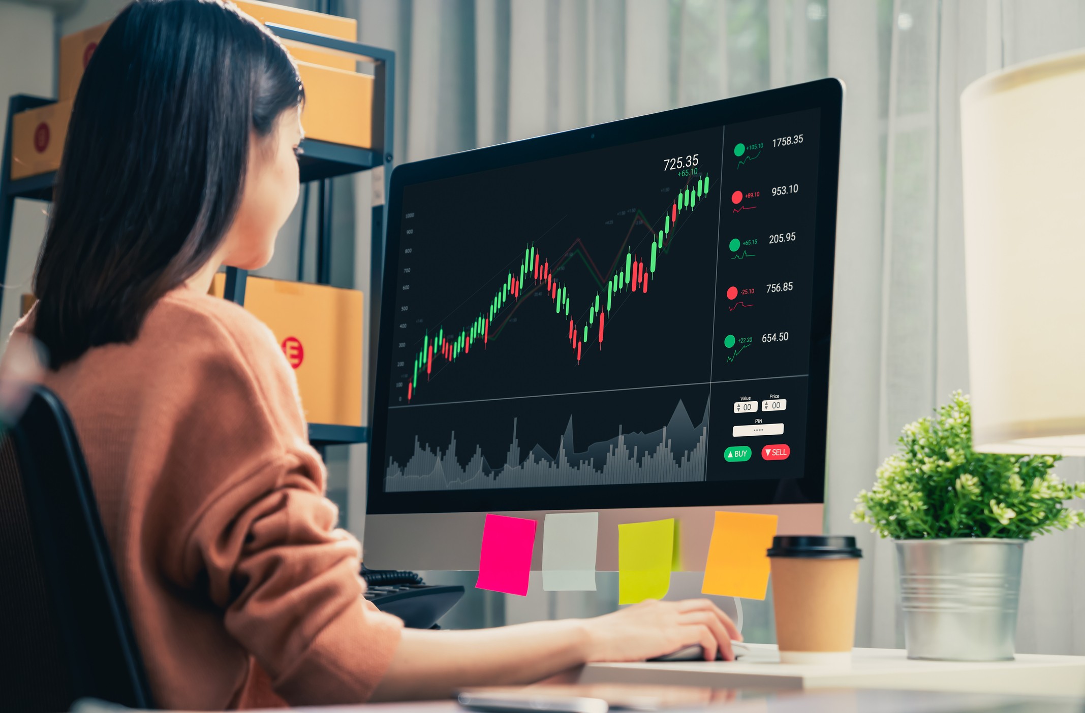 Trader looking at computer screens with trading charts and financial data
