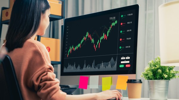 Trader looking at computer screens with trading charts and financial data