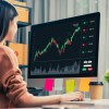 Trader looking at computer screens with trading charts and financial data