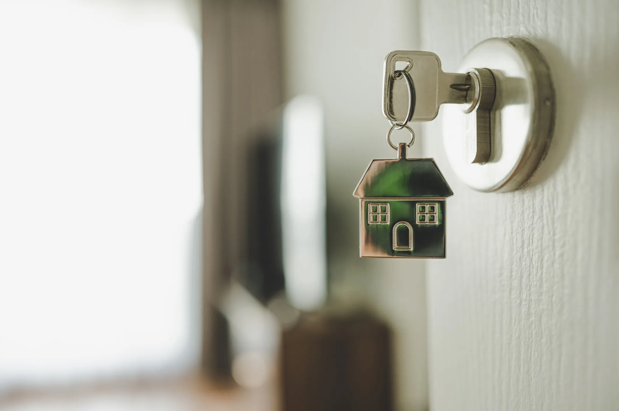 Open door and door handle with a key and a keychain-shaped house