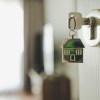 Open door and door handle with a key and a keychain-shaped house