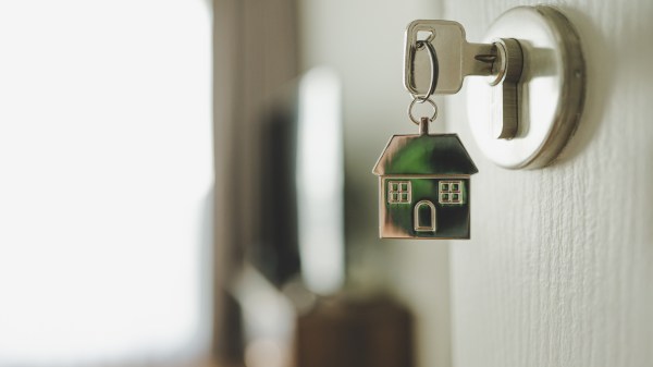 Open door and door handle with a key and a keychain-shaped house
