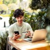 Young man sitting at the cafe and paying online with credit card