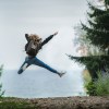 Woman jumping wearing green backpack