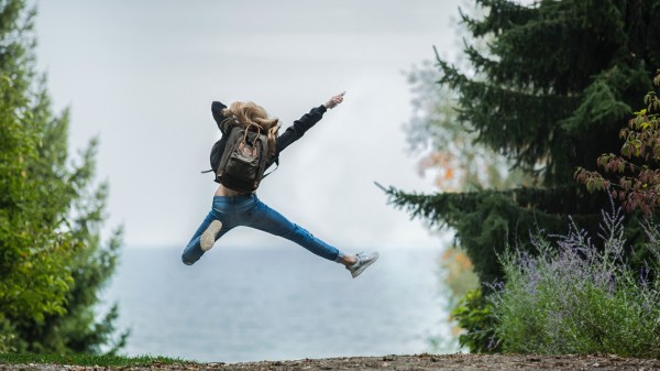 Woman jumping wearing green backpack