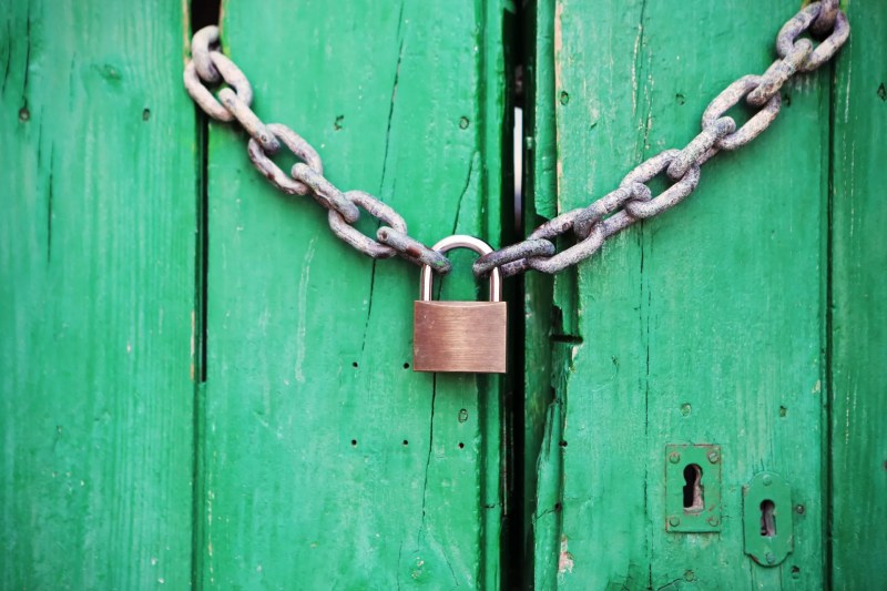 Brass-colored metal padlock with chain, representing freezing your credit
