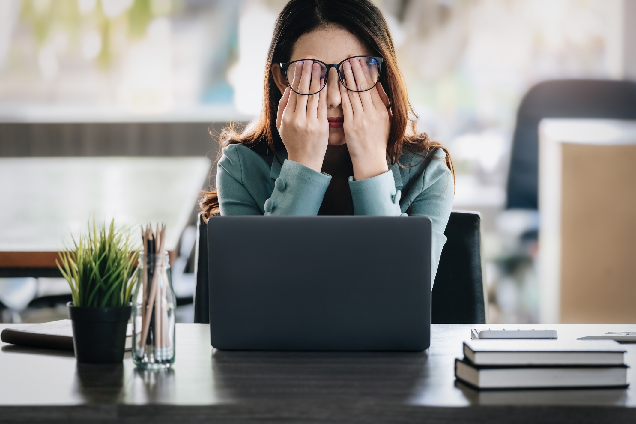 stressed out woman with hands in her face while sitting at her desk