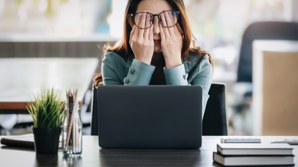 stressed out woman with hands in her face while sitting at her desk