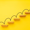 Rising arrow on staircase on yellow background