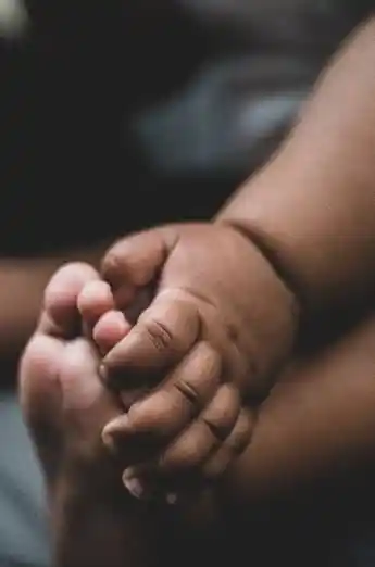 Baby hand holding baby's foot