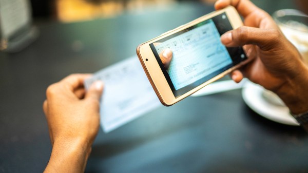 Woman depositing check by phone in a cafe
