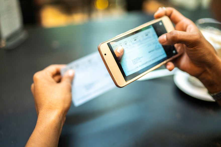 Woman depositing check by phone in a cafe