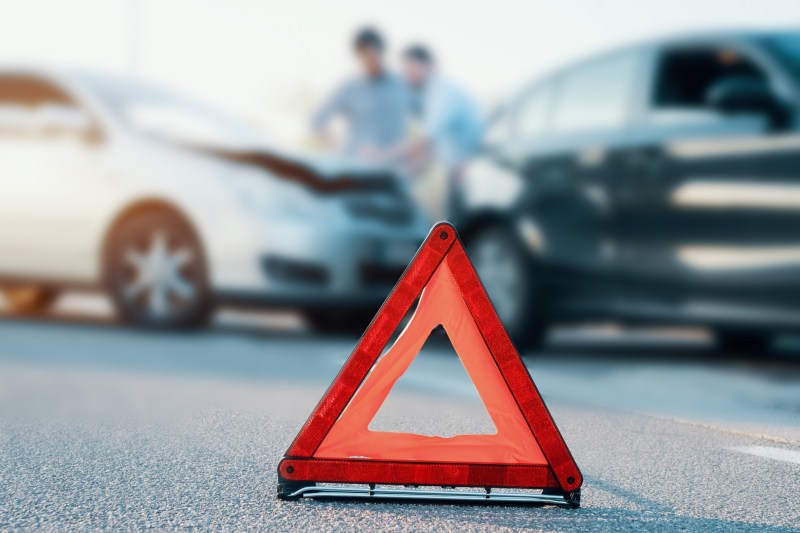 Two men reporting a car crash for the insurance claim and the main focus is on the red triangle