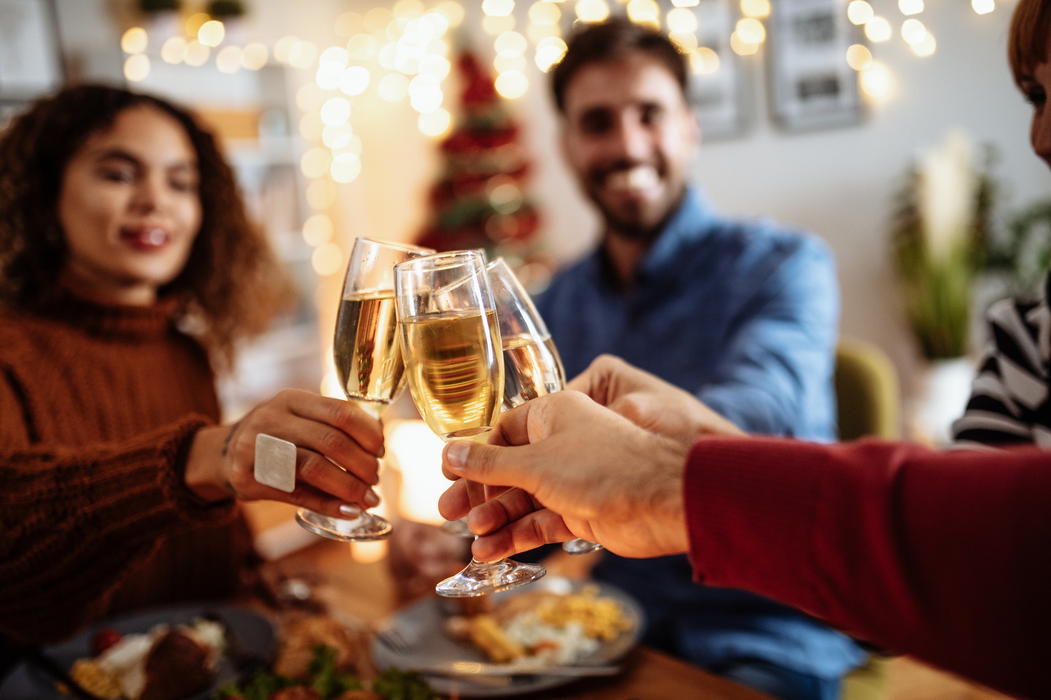 Friends celebrate Christmas and enjoying dinner while toasting with wine