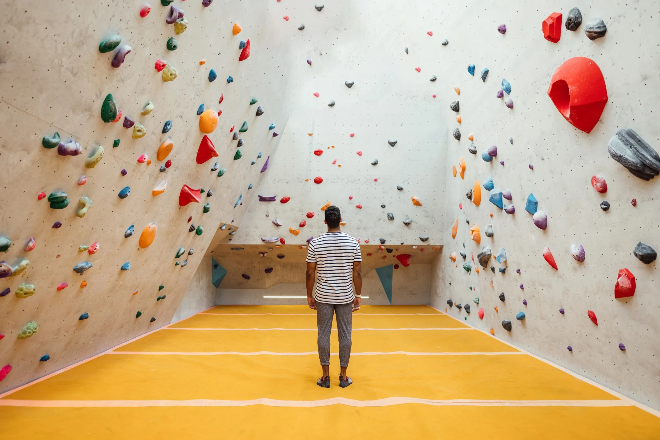 A wide angle rear view of a man looking at the expansive climbing wall at an indoor climbing centre in Newcastle Upon Tyne in the North East of England