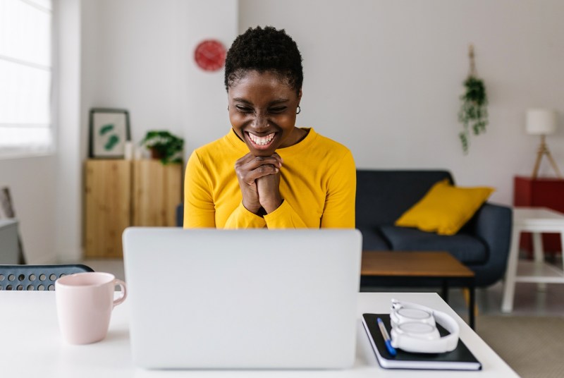 woman reading good news on computer while sitting at home office