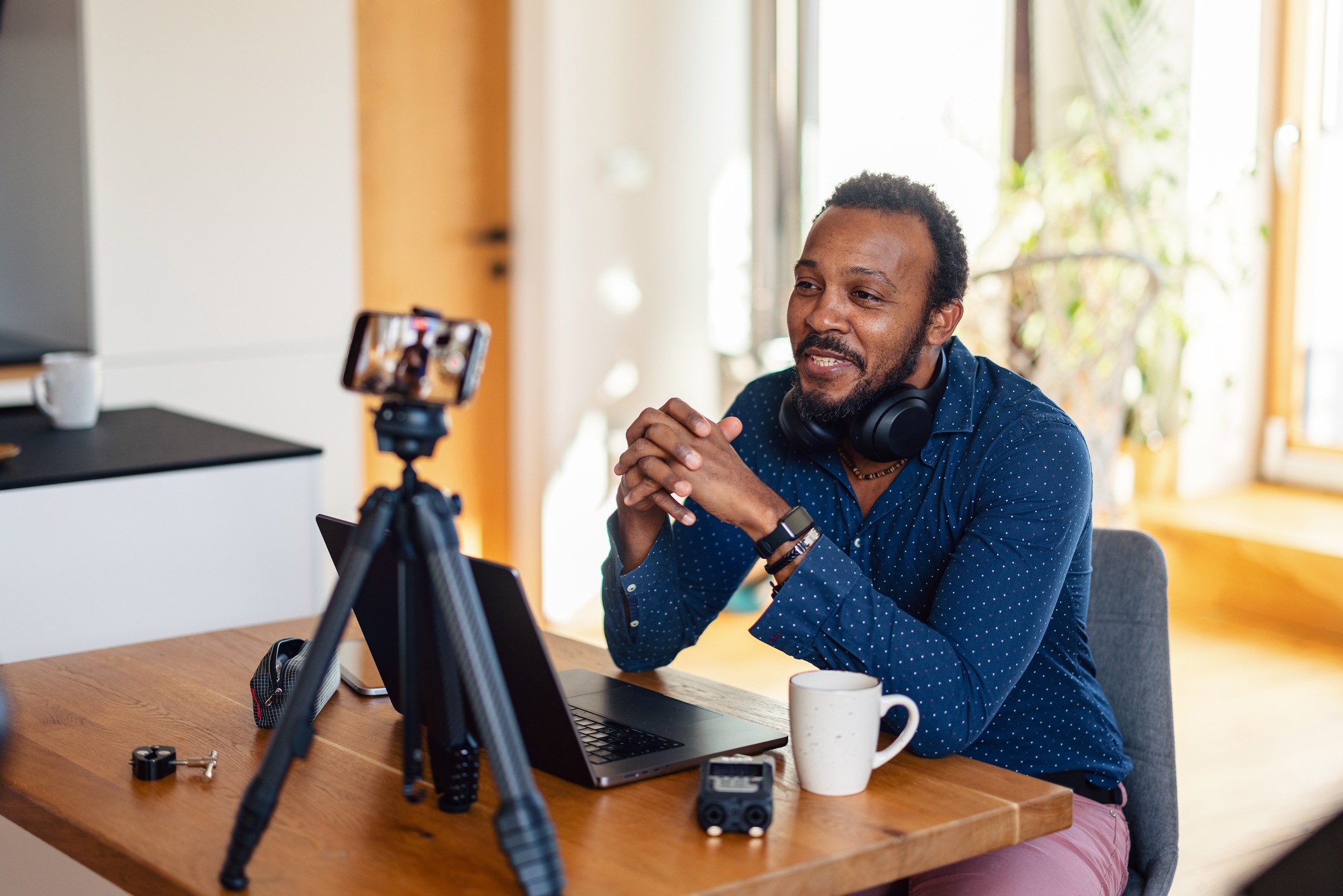 male content creator working from home, recording video content with a smartphone on a tripod