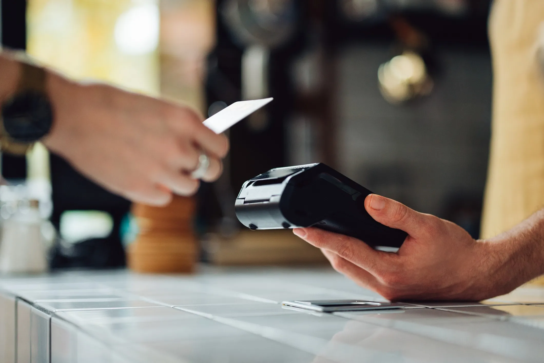 A man is holding a card machine while the other person is placing a card to pay