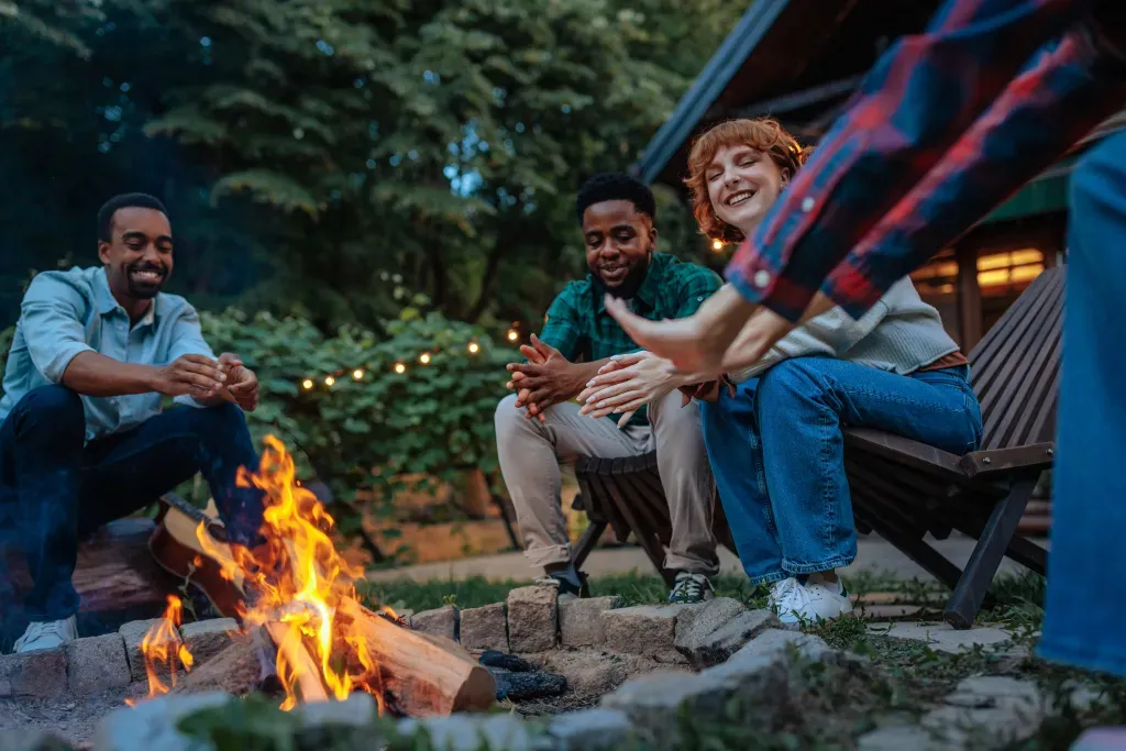 Friends warming up around bonfire in the backyard